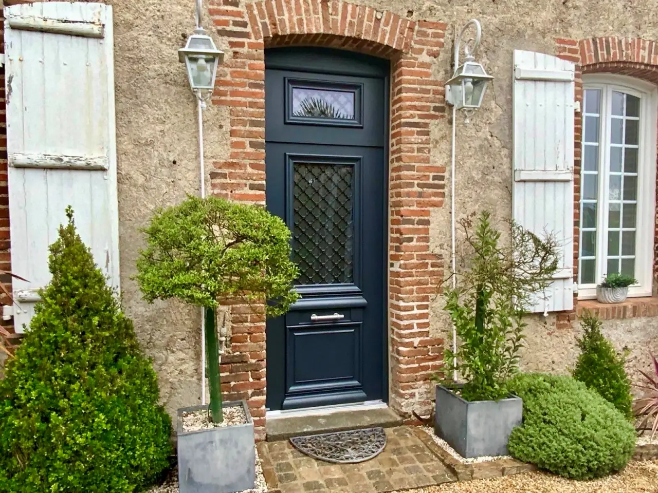 porte d'entrée en alu bleu foncé avec grille dans le vitrage pour une maison de caractère avec briques à cholet