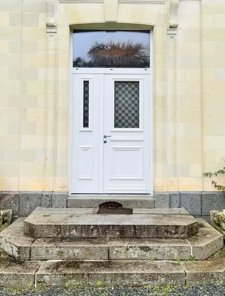 porte d'entrée blanche en bois avec vitrage et croisillons pour une entrée avec des murs en pierre