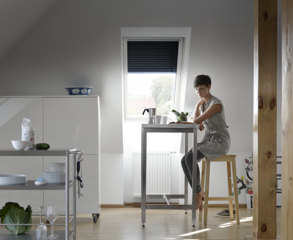 femme assise dans une cuisine devant une fenetre de toit VELUX