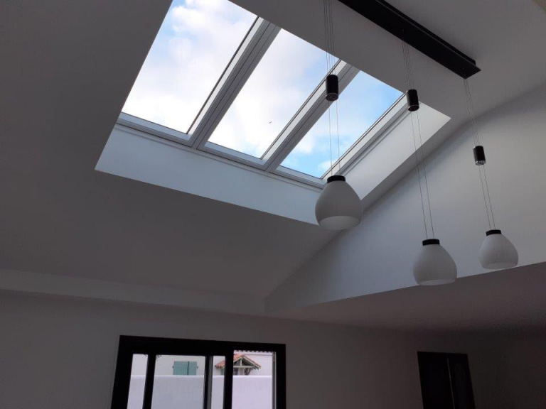 verrière 3 en 1 VELUX dans un sejour moderne avec hauteur sous plafond et lustres