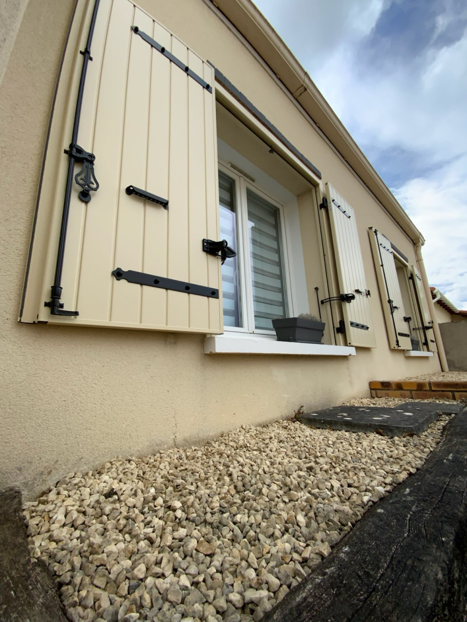 Façade de maison avec fenêtres blanches et volets battants en alu beige